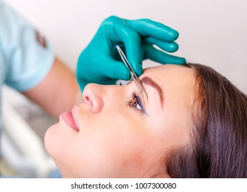 Cosmetic surgeon examining female client in office. Doctor checking woman's face, the eyelid before plastic surgery, blepharoplasty. Surgeon or beautician hands touching woman face. Rhinoplasty