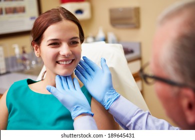 Cosmetic Surgeon Examining Female Client In Office