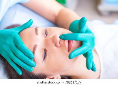 Cosmetic Surgeon Examining Female Client In Office. Doctor Checking Woman's Face, Nose Before Plastic Surgery. Surgeon Or Beautician Hands Touching Woman Face. Rhinoplasty