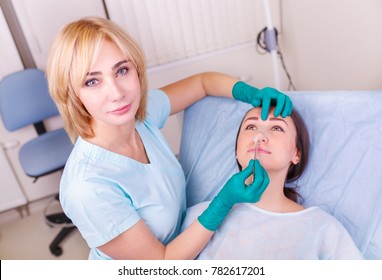 Cosmetic surgeon examining female client in office. Doctor checking woman's face, nose before plastic surgery. Surgeon or beautician hands touching woman face. Rhinoplasty