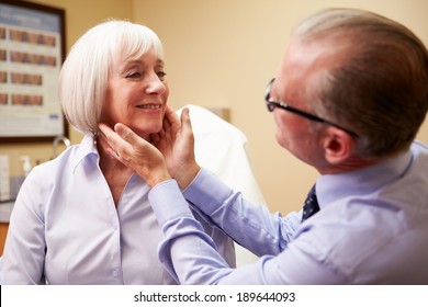 Cosmetic Surgeon Examining Senior Female Client In Office