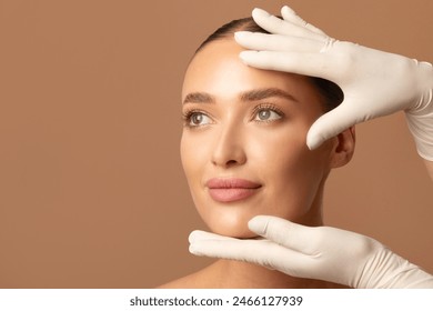 Cosmetic surgery concept. Doctor examining young woman's face, beautiful lady during visit to cosmetologist cabinet, beige studio background, copy space - Powered by Shutterstock