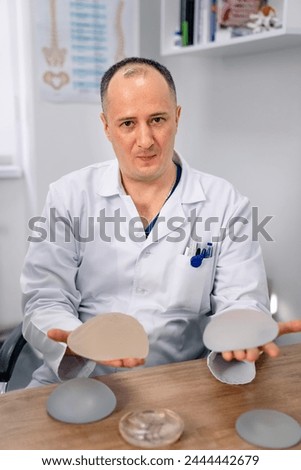 Cosmetic surgery consultation. Doctor with breast implants working at office.