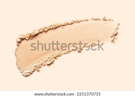 Cosmetic texture bronzer pressed powder smudge with shimmer isolated on light beige background