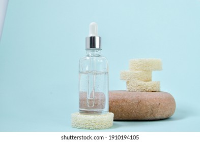 Cosmetic tonic serum in white dropper bottles on natural stone. Blue background, natural skincare products concept.