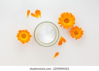 Cosmetic white container with cream and calendula,marigold flowers. Organic cosmetic concept. Flat lay,copy space.