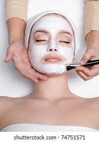 Cosmetician applying facial mask to the face of young beautiful woman in spa salon - vertical - Shutterstock ID 74751571