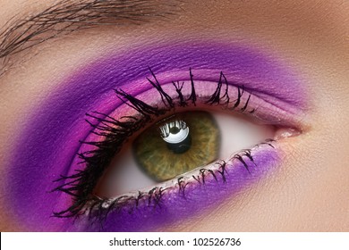 Cosmetics And Beauty Care. Macro Close-up Of Beautiful Green Female Eye With Bright Fashion Runway Make-up. Violet Eyeshadows And Black Eyeliner