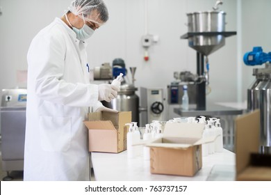 Cosmetics fabric worker taking one liquid soap from a row and putting in a paper box for transport.