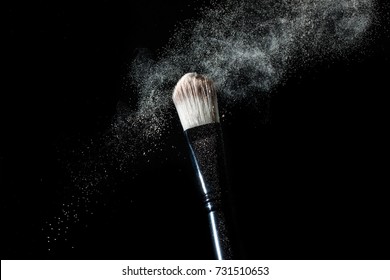 Cosmetics Makeup Brush And Powder Dust Explosion. Isolation On A Black Background.