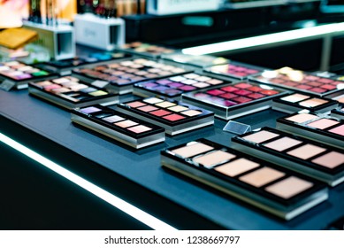 Cosmetics On The Shop Window With A Variety Of Colors And Shades, Mascara, Powder, Paint For Beauty And Makeup. Consumerism, Retail And Purchase Concept.