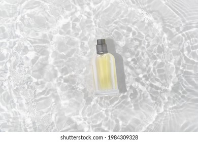 Cosmetics Perfume Bottle On Splashing Water Surface With Circles On White  Background. Glass Spray Tube Package Promo Mockup Banner Design. 

Flat Lay, Top View, Copy Space Concept.