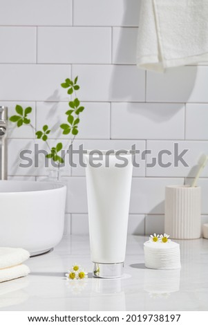 Cosmetics product and cotton towels, cottons pad with green plant on white table inside a bathroom background ceramic. Space for text