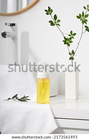Cosmetics product and cotton towels, cottons pad with green plant on white table inside a bathroom background ceramic.