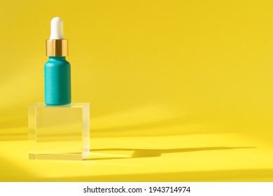 Cosmetics Serum Product With Peptide And Collagen, Hyaluronic Acid Skincare Bottle On Transparent Crystall Block. Modern Packaging With Shadows From Sun On Yellow Surface. Cosmetic Lotion Background