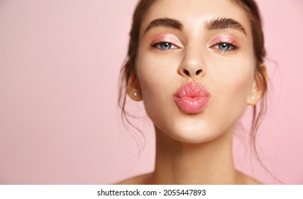 Cosméticos y cuidado de la piel. Retrato de una hermosa mujer con labios de balancín, besándose, mostrando piel facial limpia natural, parado sobre fondo rosado