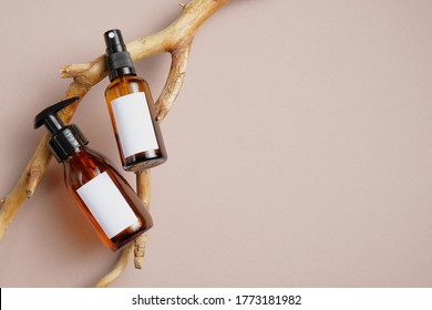 Cosmetics SPA Branding Mockup. Dark Amber Glass Bottles With White Labels For Text On Wood Branch. Pump Dispenser Bottle For Cosmetic And Body Spray Bottle. Flat Lay, Top View.