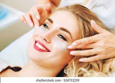 Cosmetologist applaying anti-aging eye gel pads