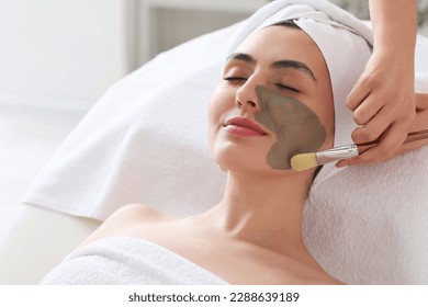 Cosmetologist applying clay mask onto young woman's face in salon, closeup - Powered by Shutterstock