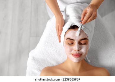 Cosmetologist applying mask on woman's face in spa salon, top view. Space for text - Powered by Shutterstock