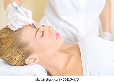 Cosmetologist applying permanent make up on eyebrows
