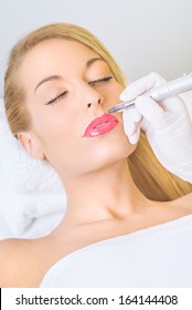 Cosmetologist applying permanent make up on lips