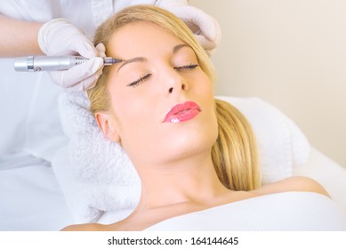 Cosmetologist applying permanent make up on eyebrows