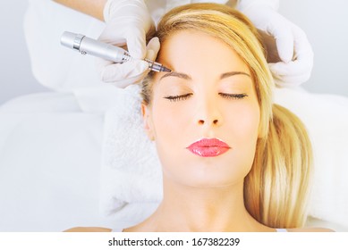 Cosmetologist applying permanent make up on eyebrows