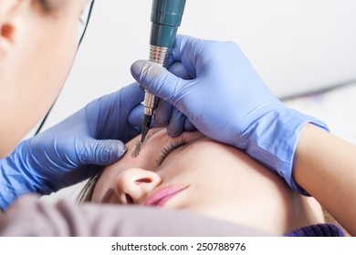 Cosmetologist applying permanent make up on eyebrows- eyebrow tattoo
