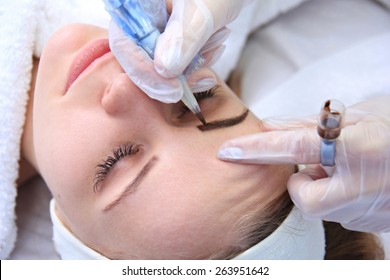 Cosmetologist applying permanent make up on eyebrows- eyebrow tattoo