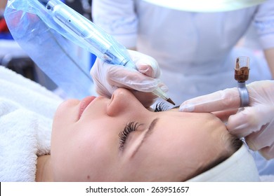 Cosmetologist applying permanent make up on eyebrows- eyebrow tattoo