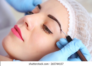 Cosmetologist applying permanent make up on eyebrows