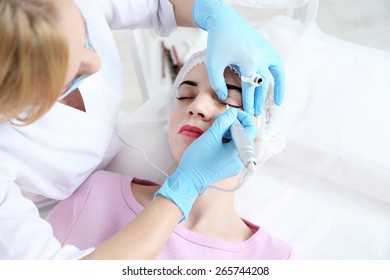 Cosmetologist applying permanent make up on eyes, close-up