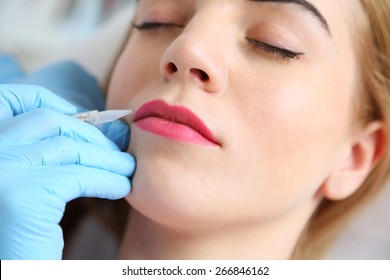 Cosmetologist applying permanent make up on lips