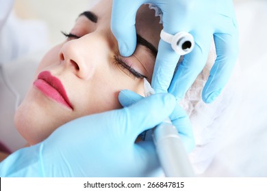 Cosmetologist applying permanent make up on eyes, close-up