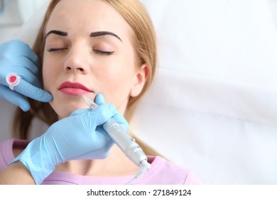 Cosmetologist applying permanent make up on lips