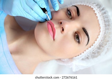 Cosmetologist applying permanent make up on lips
