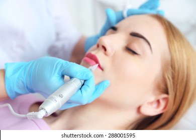 Cosmetologist applying permanent make up on lips