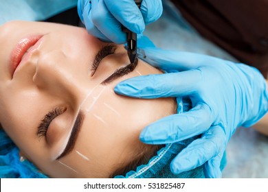 Cosmetologist applying permanent make up on eyebrows- eyebrow tattoo