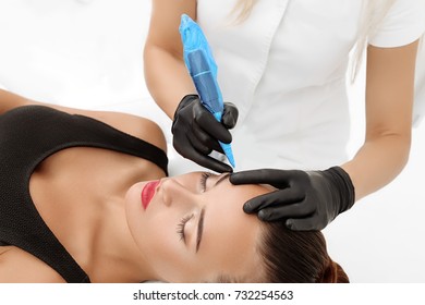 Cosmetologist applying permanent make up on eyebrows- eyebrow tattoo