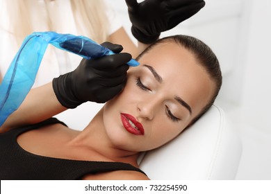 Cosmetologist applying permanent make up on eyebrows- eyebrow tattoo