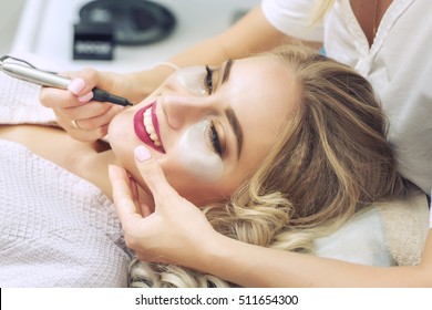 Cosmetologist applying permanent make-up on lips