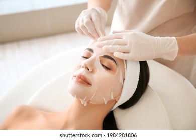 Cosmetologist applying sheet mask on woman's face in beauty salon - Shutterstock ID 1984281806