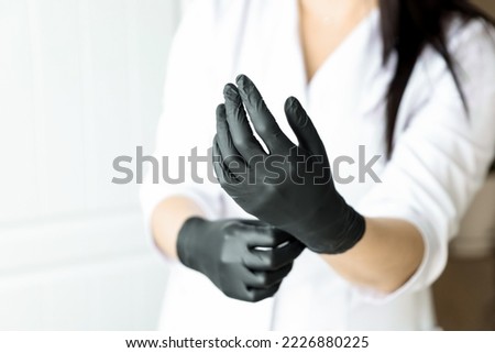 Cosmetologist or doctor woman hands in black latex gloves on white background prepairing for a procedure or operation