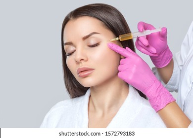 Cosmetologist does prp therapy on the face of a beautiful woman with clean skin in a beauty salon. There is in vitro blood plasma, ready for injection. Cosmetology concept.