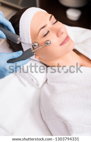cosmetologist doing lifting massage on woman face at beauty salon