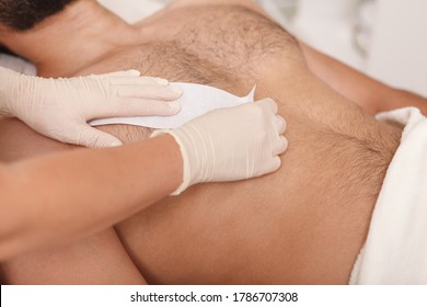 Cosmetologist doing waxing on torso of unrecognizable male client - Shutterstock ID 1786707308