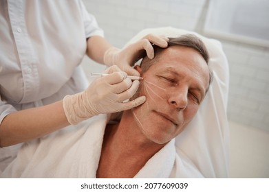 Cosmetologist drawing guidelines for injection of cosmetic product with white pencil. Thread facelift with arrows for male skin, facial contouring procedure with meso threads for facial rejuvenation - Shutterstock ID 2077609039