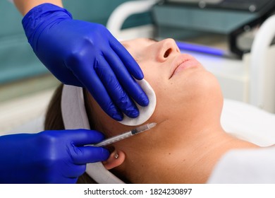 Cosmetologist Hands In Blue Gloves Hold Syringe With Needle And Liquid Filler, Botox And Cotton Pad During Injection Beauty Skincare Procedure Close Up