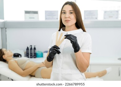 Cosmetologist holds sticks for epilation with sugar in his hands - Shutterstock ID 2266789955